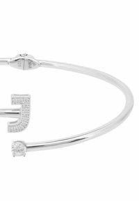 Ezüst karkötő, amelyen egy nagybetűs „J” található, apró gyémántokkal díszítve, az ellenkező oldalon pedig egyetlen kerek kővel. Jelzéssel ellátva: 925.