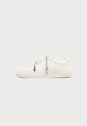 Λευκό sneaker χαμηλού προφίλ με υφασμάτινα κορδόνια και μικρές διακοσμητικές χάντρες στο πλάι, σε απλό φωτεινό φόντο.