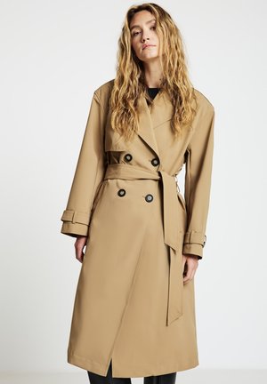 Knielanger beige Trenchcoat aus weichem Stoff mit doppelreihiger Vorderseite, tailliertem Gürtel und geknöpften Manschetten. Verfügt über einen hohen Kragen.