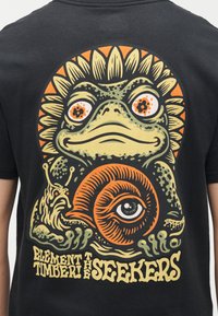 Πράσινος βάτραχος με μεγάλα πορτοκαλί μάτια κρατάει ένα μεγάλο πορτοκαλί σαλιγκάρι με ένα κεντρικό μάτι, πέταλα ηλίανθου πίσω από τον βάτραχο και στιλιζαρισμένο κείμενο από κάτω.