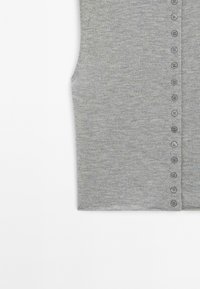 Grå ärmlös topp i mjukt stickat tyg med framknäppning och matchande knappar samt en slät textur.