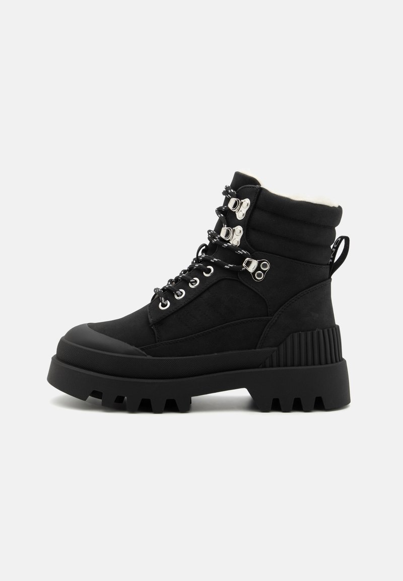 Bottines noires à chevilles avec un dessus rembourré, des accents texturés, un matériel métallique, des lacets, et une semelle en caoutchouc épaisse présentant un motif dentelé.