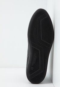 Černá podrážka boty s texturovaným vzorem pro lepší přilnavost, viditelné jméno značky "Kagabond Shoemakers" a velikost číslo 35 na podrážce.