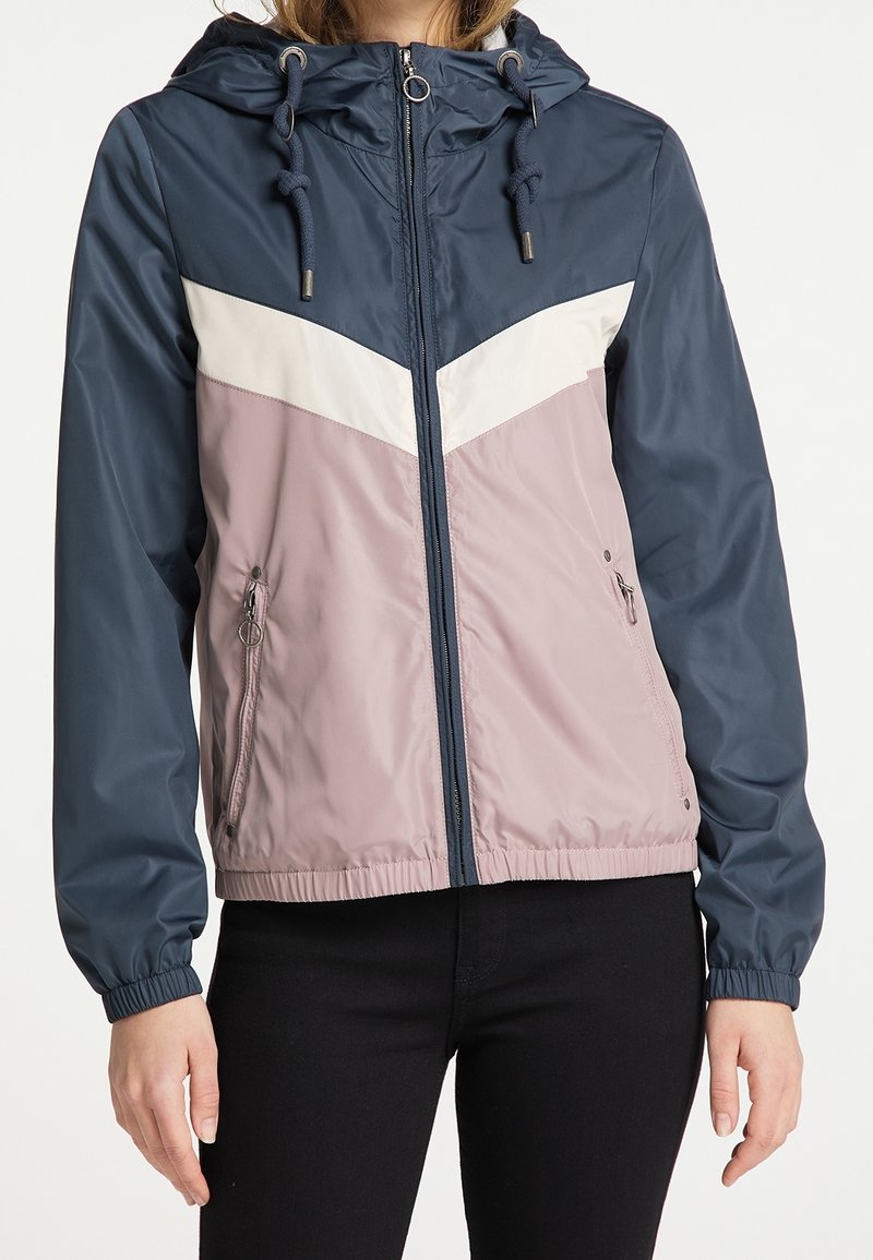 Giacca leggera con cappuccio in blu navy, bianco e malva. Presenta una chiusura zip frontale, polsi elasticizzati e due tasche laterali. Tessuto liscio e resistente all'acqua.
