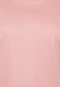 Lys rosa bomull t-skjorte med en jevn tekstur, rund halslinje og korte ermer, uten synlige mønstre eller dekorasjoner.