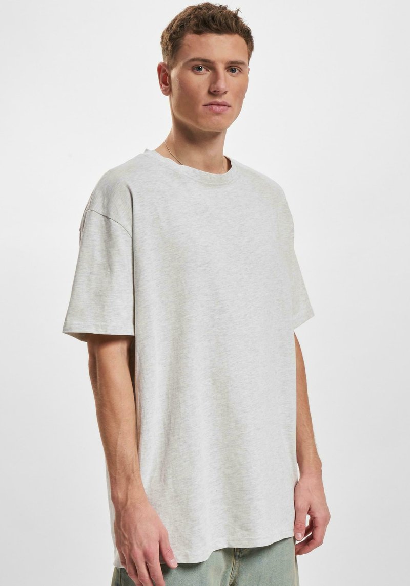 Lys grå oversized t-skjorte laget av myk stoff, med rund hals, korte ermer og en avslappet passform.