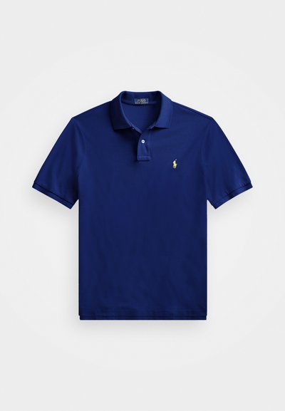 Temno modra polo majica iz mehkega bombaža, z zapiranjem na tri gumbe, kratkimi rokavi in rumenim logotipom na levem prsnem delu.