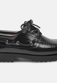 Schwarze Lederschuhe mit glänzender Oberfläche, runder Spitze, Schnürdesign und strukturierter Gummisohle mit tiefen Profilen für Grip und Stabilität.