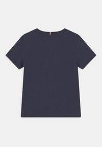 Marineblaues T-Shirt mit kurzen Ärmeln, runder Ausschnitt, aus Baumwolle, mit einem kleinen dreieckigen Design am hinteren Halsbereich in rot und weiß.