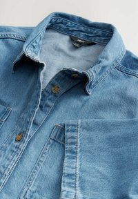 Hele sinine denim särgiga kaelusega, kahe rinnataskuga ja nööbid. Omab pehmet tekstuuri ja peeneid õmbluse detaile.