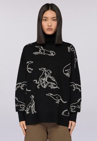 Schwarzer Strickpullover mit hohem Kragen, der weiße Umrissmuster von Hunden aufweist. Lockere Passform mit langen Ärmeln.