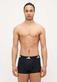 Boxer briefs negros hechos de una tela suave con una cintura elástica que presenta rayas diagonales blancas. El diseño es liso, sin costuras visibles.