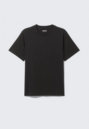 Camiseta de algodón negra con cuello redondo y mangas cortas, que presenta un diseño minimalista y un sutil logo de "WEEKDAY" en el cuello.
