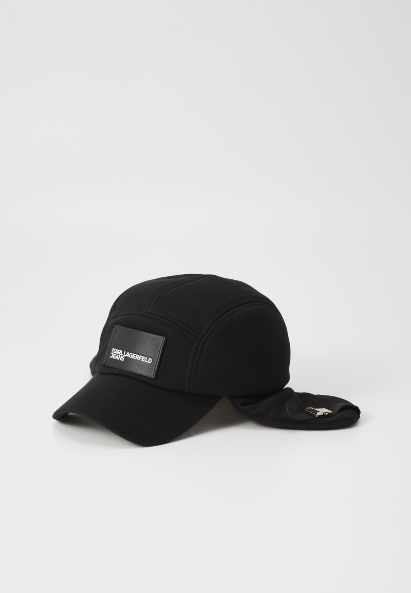 Black cap made of textured fabric with a round visor. Features a rectangular logo patch on the front and flaps on the sides.