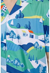 Camicia a maniche corte con stampa paesaggistica colorata in verde, blu e bianco, con alberi astratti, case e barche. Tessuto leggero.