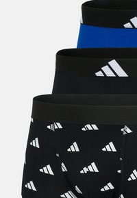 Tre par herrkalsonger: ett par blå, två par svarta med vita trekantiga mönster, med svarta elastiska midjeband med logotypdetaljer.