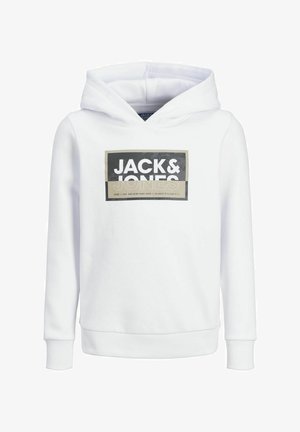 Person trägt weißen Jack & Jones Hoodie, schwarze Hosen mit weitem Bein und schwarz-weiße Turnschuhe, steht vor einfarbig hellem Hintergrund.