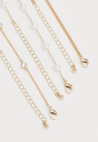 Gold chain accessory featuring varying designs: smooth links, alternating pearls, and crystals, each ending with a lobster clasp and ball details.