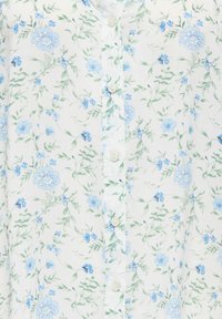 Tissu blanc avec motif floral bleu clair et vert et boutons blancs au centre.