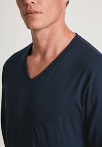 Marineblauwe V-hals t-shirt van zachte stof, met een borstzak aan de linkerkant en een subtiele textuur, met een relaxte pasvorm en nette stiksels.