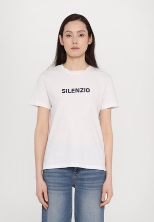 T-shirt en coton blanc à manches courtes et col rond, avec "SILENZIO" imprimé en bleu marine sur la poitrine. Porté avec un jean bleu.