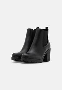 Schwarze Stiefeletten mit einer glatten Lederoberfläche, elastischen Seiteneinsätzen, einer strukturierten Sohle und einem dicken Absatz für zusätzliche Höhe und Stabilität.