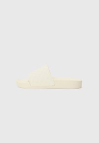 Beige schuifl sandal met een gestructureerde bovenkant met een subtiel geometrisch patroon, een low-profile zool en lichte padding voor comfort.
