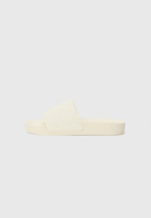 Beige slide sandal with a textured upper featuring a subtle geometric pattern, low-profile sole, and slight padding for comfort.