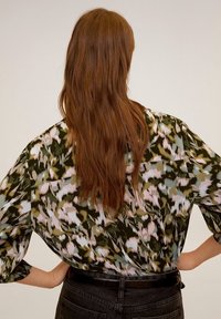 Blouse ample avec un motif abstrait multicolore dans des nuances de vert, rose et bleu; manches longues et ourlet droit.