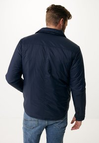 Tmavě modrá prošívaná bunda s límcem, viditelným šitím a bočními kapsami. Texturovaná tkanina s hladkým povrchem.