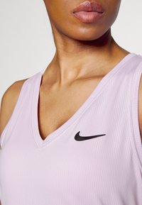 V-neck athletic tank top in light lavender fabric with a textured finish and a small black Nike logo on the left chest area.