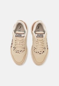 Baskets Puma beige avec des accents imprimé léopard sur l'orteil et les côtés, lacets blancs et logo Puma sur la languette, vues de dessus sur fond blanc.