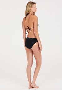 Set bikini nero caratterizzato da un top bandeau con laccio al collo e pantaloni a vita alta a coste, che mostrano una finitura testurizzata.