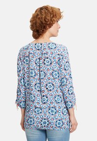 Dreiviertelarm-Bluse in einem blauen, korallenfarbenen und weißen Blumenmuster. Sie hat einen runden Halsausschnitt und einen lockeren Schnitt mit Kordelzug-Manschetten.