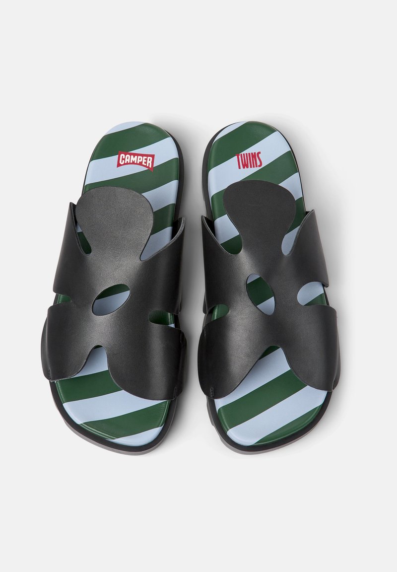 Schwarze Sandalen mit einem abstrakten Riemendesign. Der Fußbett hat ein gestreiftes Muster in Grün und Hellblau. Die Markennamen "CAMPER" und "TWINS" sind sichtbar.