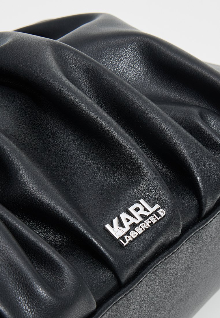 Bolso de mano plisado de cuero sintético negro con una etiqueta plateada del logo "KARL LAGERFELD", que presenta una superficie suave y texturada, así como una forma estructurada.