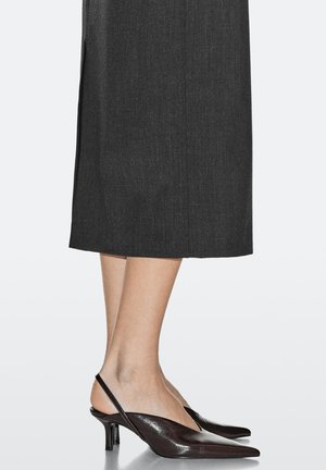 Braune Slingback-Pumps mit spitzen Zehen, aus Leder, mit niedrigem Absatz und glatter Textur, kombiniert mit einem dunklen knielangen Rock.