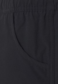 Black fabric garment featuring an elastic waistband, side pocket detail, and smooth texture with visible stitching.
