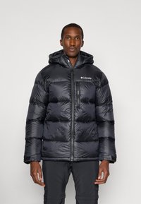 Schwarze Daunenjacke mit Kapuze, ausgestattet mit einem Reißverschluss vorne, elastischen Bündchen und diagonaler Steppung. Columbia-Logo auf der oberen linken Brust.