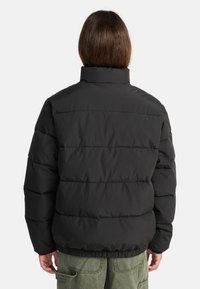 Giubbotto imbottito nero, design trapuntato con righe orizzontali, colletto alto, orlo e polsini elastici. Materiale esterno liscio e lucido, isolamento caldo.