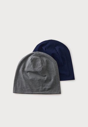 Zwei weiche, faltenstrukturierte Strickmützen, eine graue und eine marineblaue, auf einfachem weißen Hintergrund platziert.