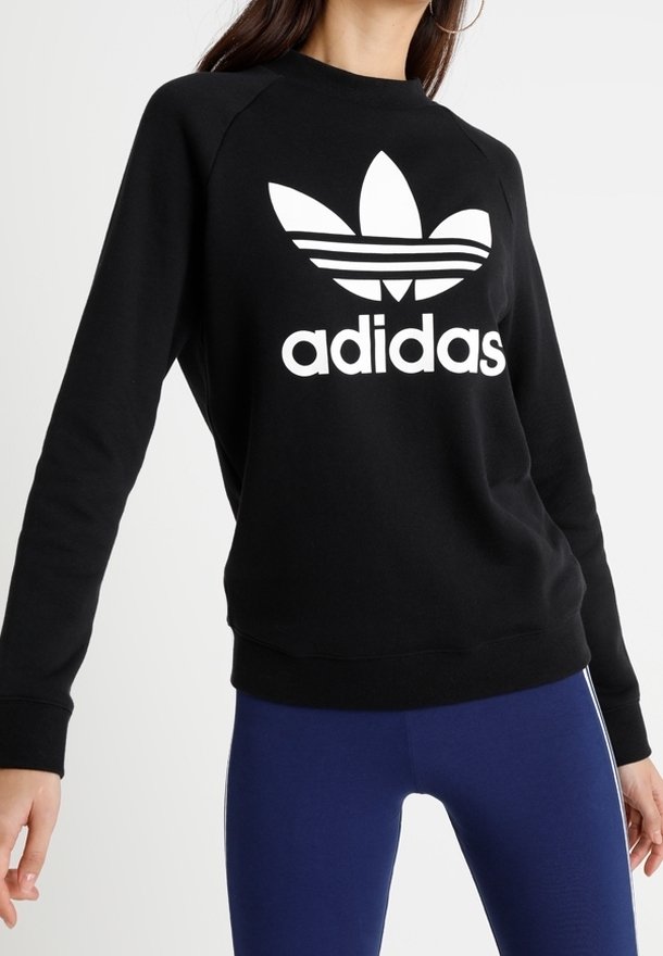 Czarny sweatshirt z białym logo Adidas i trzema paskami. Posiada okrągły dekolt oraz ściągacze na rękawach i w dolnej części. Wykonany z miękkiego materiału.