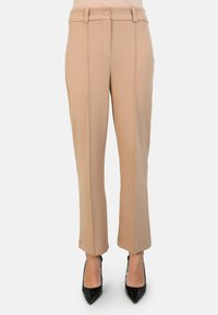 Pantalones beiges de corte recto, con cierre de un solo botón y bolsillos delanteros minimalistas. Textura de tela suave.
