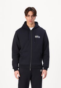 Navy Zip-Hoodie aus Baumwollmischung, mit aufgedrucktem Logo auf der Vorderseite, zwei Taschen und einer doppelt verstellbaren Kapuze. Gerippte Manschetten und Saum.
