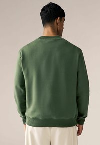 Groene sweatshirt met een ontspannen fit, ribbelboorden en -zoom. Zachte textuur, ronde halsontwerp, naadloze rug, minimalistische stijl.