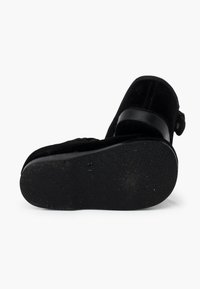 Stivale in suede nero con suola in gomma, caratterizzato da una finitura liscia e una punta arrotondata. Include un dettaglio a fascia nella parte superiore.