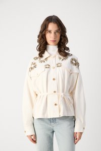 Camicia button-up color crema con un design floreale ricamato, cintura a cravatta e bottoni dorati. Presenta un colletto classico e maniche lunghe.
