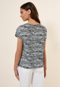Schwarz-weiß gestreiftes Kurzarmoberteil mit einem Schlüsselaugenrücken-Detail, aus leichtem Stoff gefertigt. Das Design bietet einen lässigen Schnitt.