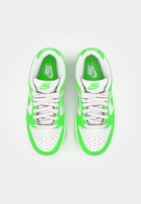 Nike sportcipők, élénk zöld felsőrésszel, fehér bőr díszítéssel, perforált orrú résszel és szürke fűzőkkel. Logó a nyelvén és a talpbetétekben.