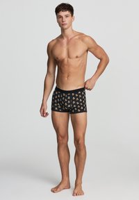 Pantaloni boxer neri con un motivo di piccoli orsetti marroni, realizzati in tessuto morbido, con una comoda cintura elastica e un design aderente.